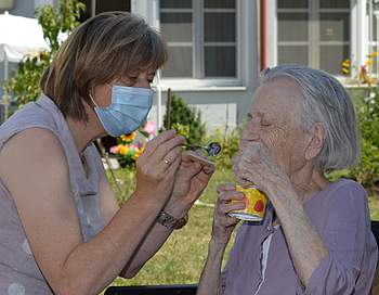 Eine Bewohnerin und eine Betreuerin essen Eis.