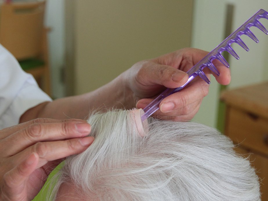 Eine Friseurin bürstet die Haare einer Bewohnerin.